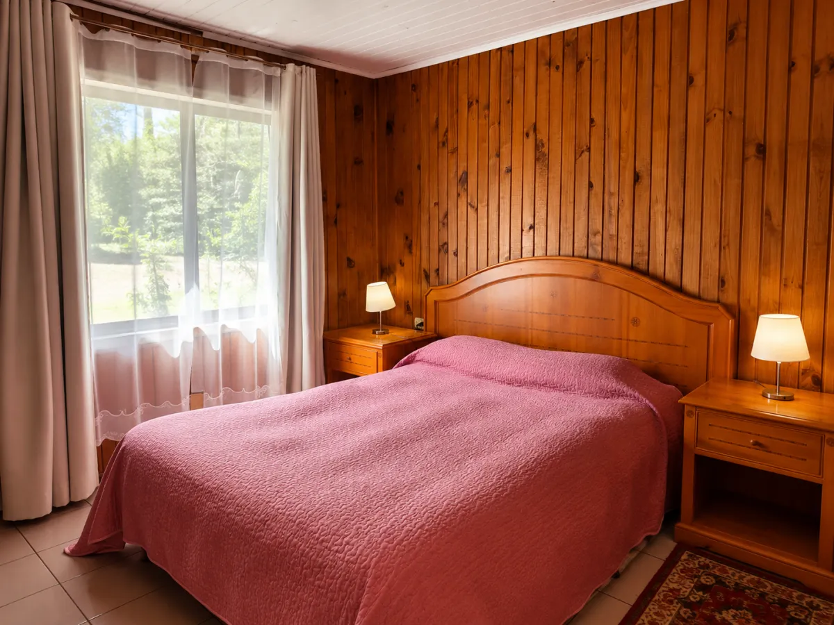 Dormitorio con revestimiento de madera y ventanal al bosque