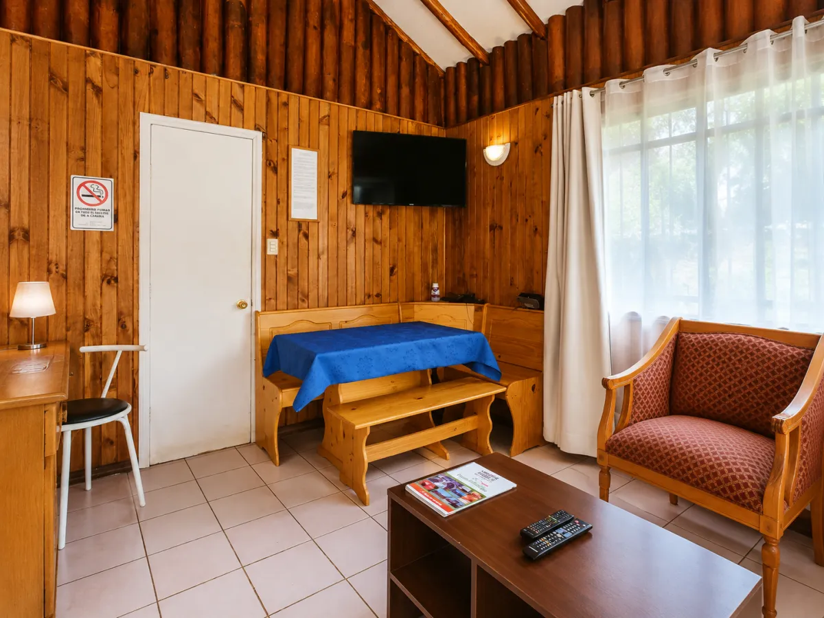 Living comedor de la cabaña, con mesa, sofá y televisor